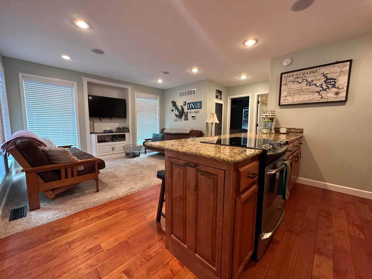 A spacious interior shot that captures the kitchen island, sofa, TV area, and a map on the wall. The arrangement encourages both relaxation and interaction, with clear sight lines that promote togetherness and easy movement between activities.