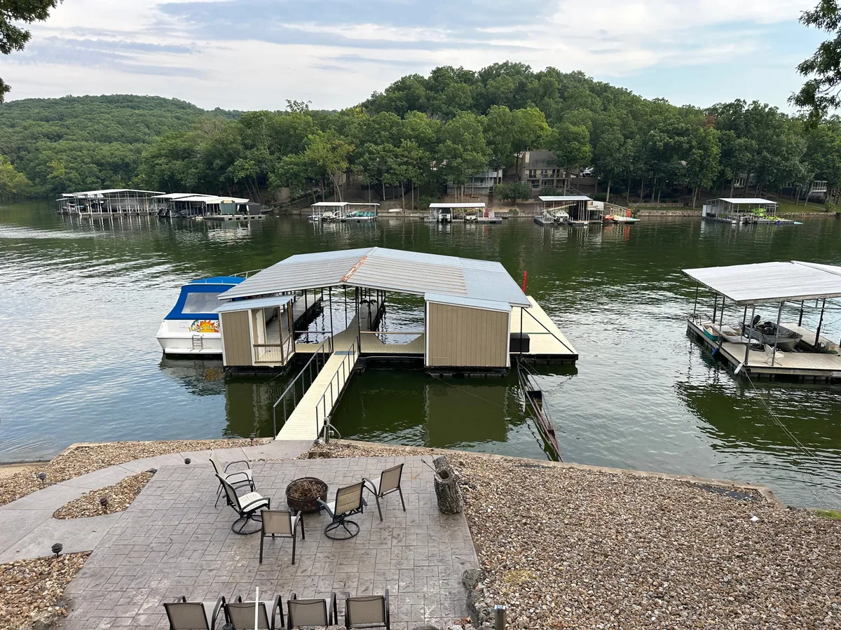 A serene dock surrounded by trees, featuring a lakeside seating area perfect for gatherings or quiet reflection. The expansive view of the lake showcases immediate access to water activities and an inviting environment for fishing or bonfires.