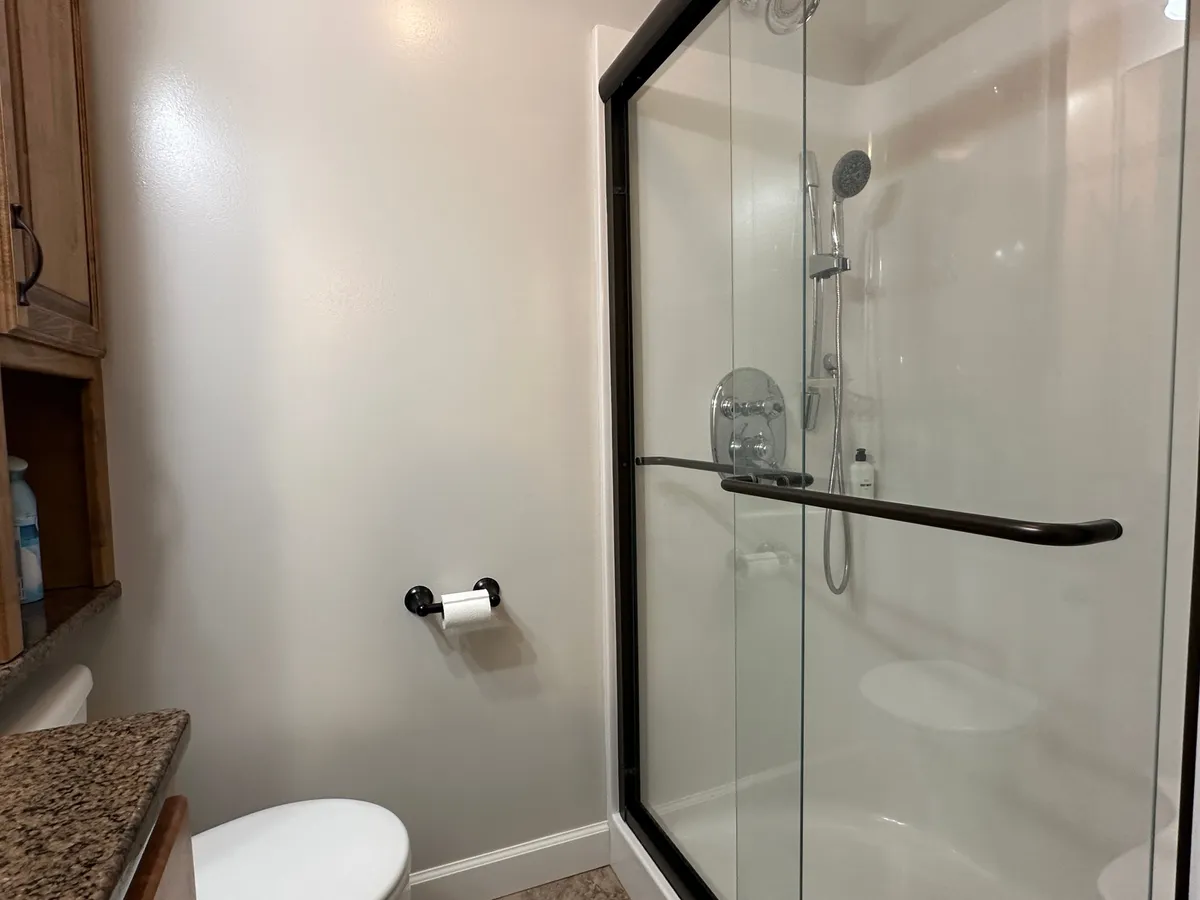 A contemporary bathroom featuring a glass shower enclosure, granite countertop, and modern fixtures, evoking a sense of tranquility and refreshment ideal for self-care routines.