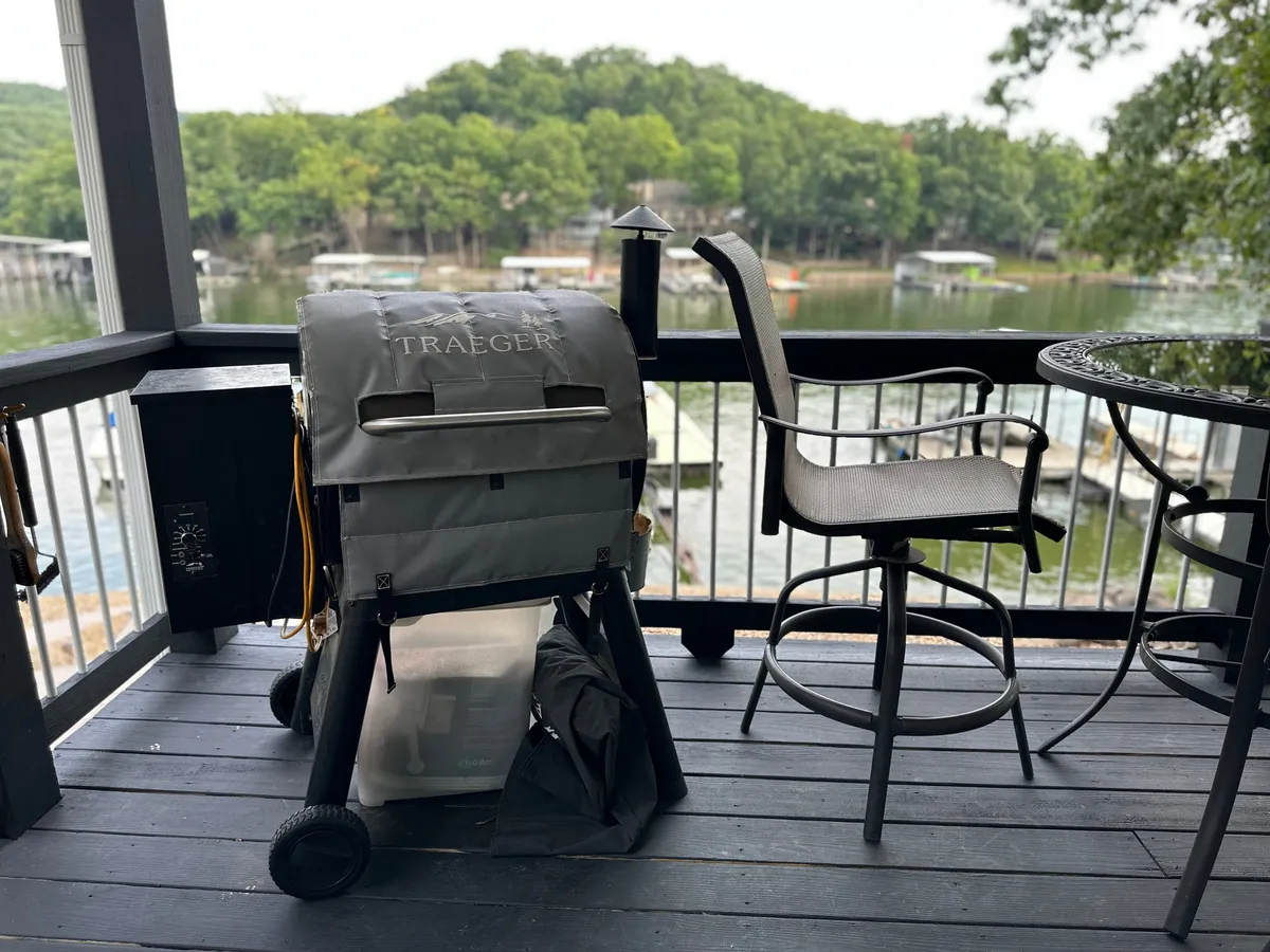 An inviting outdoor deck with a grill and barstool, overlooking a tranquil lake. The sunset light creates a warm, welcoming atmosphere, ideal for enjoying meals or socializing outside.